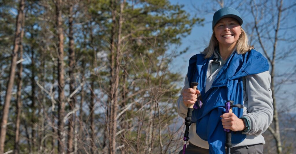 Krónikus gyulladás a szervezetben: 8 figyelmeztető jel, amit nem szabad figyelmen kívül hagyni 1 Krónikus gyulladás elleni mozgás – mosolygó nő Nordic Walking botokkal az erdőben